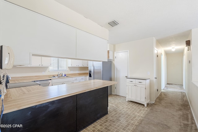 kitchen with white cabinetry, sink, stainless steel appliances, kitchen peninsula, and light carpet