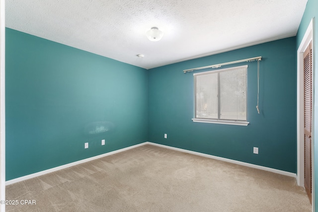 spare room featuring a textured ceiling and light carpet