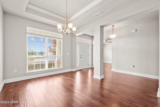 spare room with ceiling fan with notable chandelier, dark hardwood / wood-style flooring, a tray ceiling, and crown molding