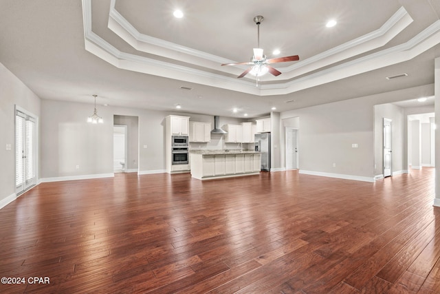 unfurnished living room featuring a raised ceiling, ornamental molding, and dark hardwood / wood-style floors