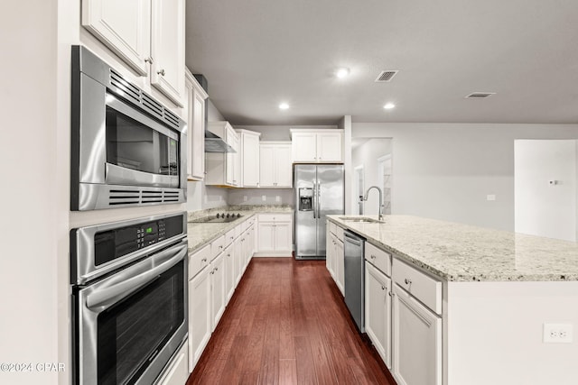 kitchen featuring stainless steel appliances, a center island with sink, white cabinets, and light stone countertops