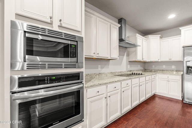 kitchen featuring white cabinetry, light stone countertops, dark hardwood / wood-style flooring, wall chimney range hood, and appliances with stainless steel finishes