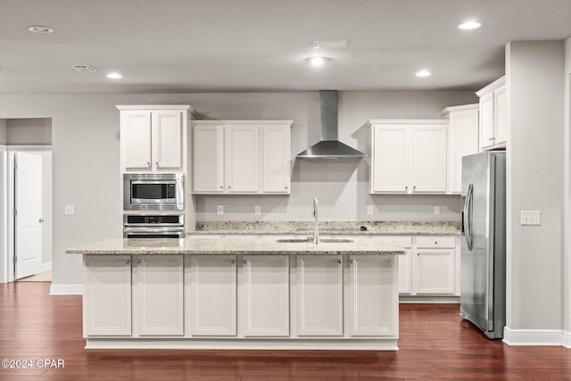 kitchen featuring an island with sink, wall chimney range hood, white cabinets, appliances with stainless steel finishes, and sink