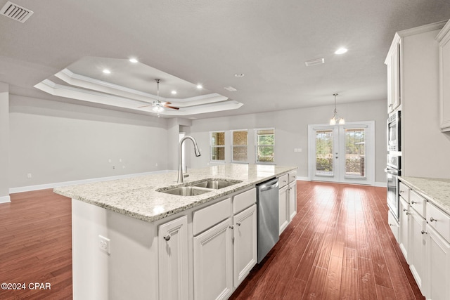 kitchen with sink, stainless steel appliances, a raised ceiling, and a kitchen island with sink