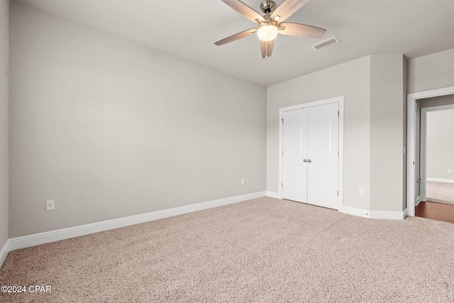 unfurnished bedroom with light colored carpet, ceiling fan, and a closet