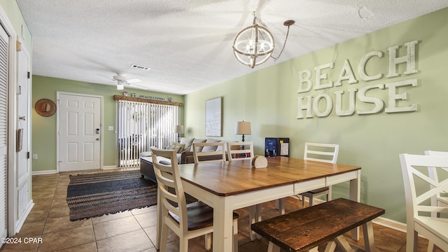 tiled dining area with baseboards, visible vents, a textured ceiling, and ceiling fan with notable chandelier