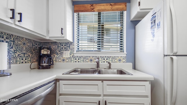 kitchen with a sink, white cabinets, light countertops, stainless steel dishwasher, and freestanding refrigerator