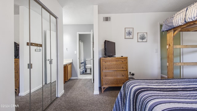 bedroom with baseboards, visible vents, ensuite bathroom, a textured ceiling, and dark carpet