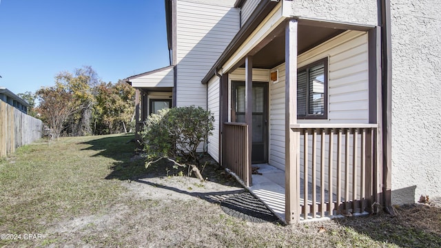 doorway to property with a yard, fence, and stucco siding