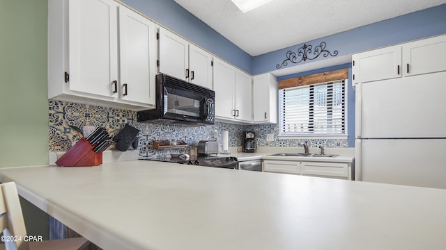 kitchen featuring freestanding refrigerator, black microwave, light countertops, and a sink