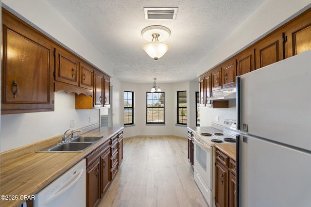 kitchen with white appliances, sink, a textured ceiling, light hardwood / wood-style floors, and a chandelier