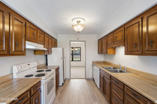 kitchen with sink, a chandelier, white appliances, and light hardwood / wood-style flooring