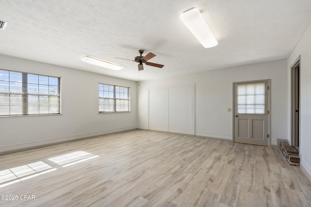 spare room with a textured ceiling, light wood-type flooring, and ceiling fan