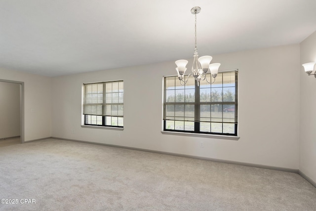 carpeted empty room featuring an inviting chandelier