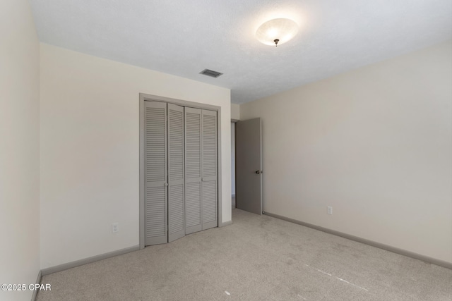 unfurnished bedroom with light carpet and a closet