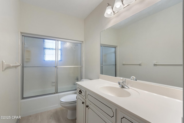 full bathroom featuring wood-type flooring, vanity, toilet, and bath / shower combo with glass door