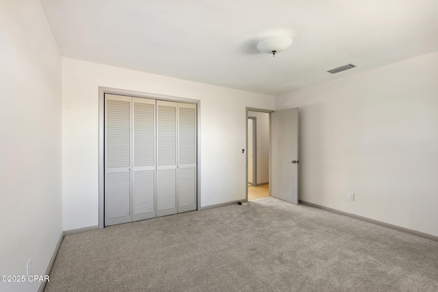 unfurnished bedroom with light carpet and a closet