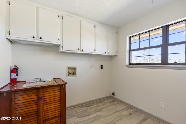 laundry room featuring electric dryer hookup, light hardwood / wood-style flooring, cabinets, and washer hookup