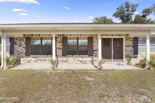 view of exterior entry featuring a lawn and a porch