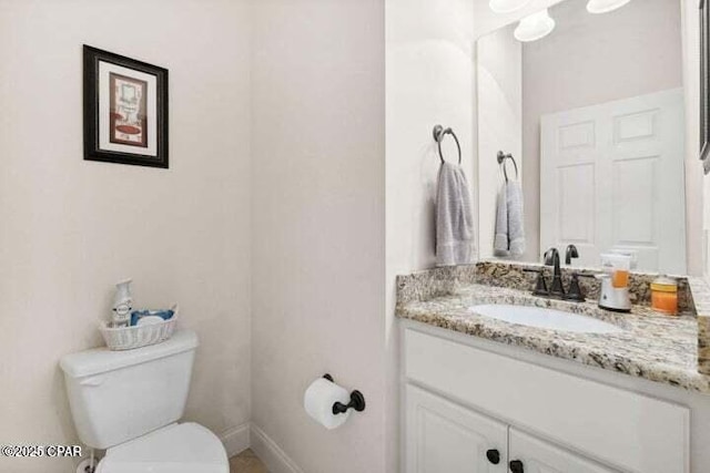 bathroom featuring baseboards, toilet, and vanity