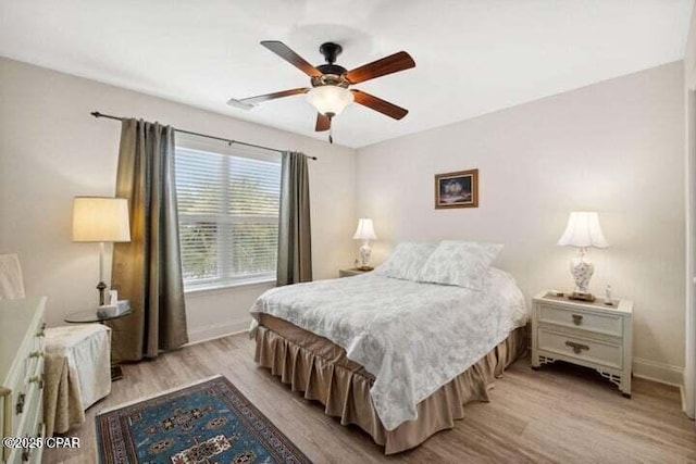 bedroom with light wood-style flooring, a ceiling fan, and baseboards