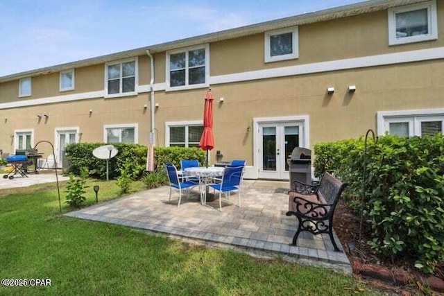 rear view of house featuring a patio area, a yard, french doors, and stucco siding