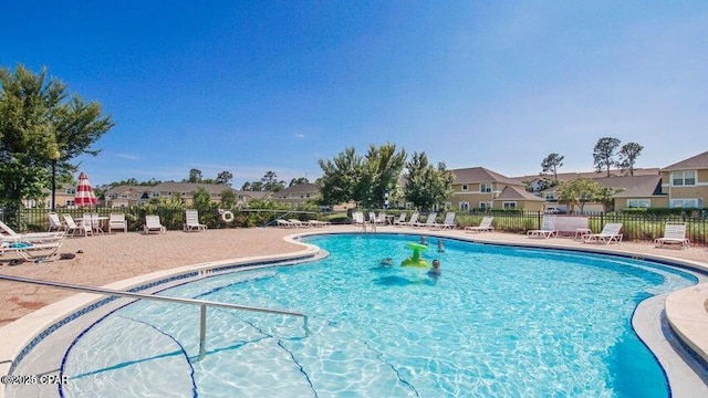 community pool with a patio and fence