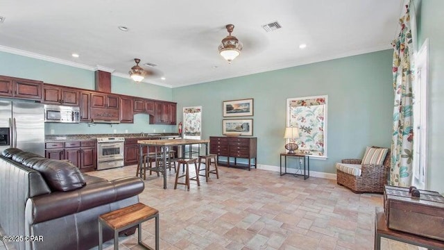 kitchen with baseboards, ceiling fan, ornamental molding, stainless steel appliances, and stone finish floor