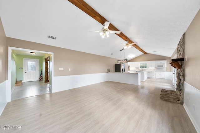 unfurnished living room featuring vaulted ceiling with beams, ceiling fan, light wood-type flooring, a textured ceiling, and a fireplace