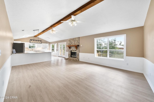 unfurnished living room with a fireplace, lofted ceiling with beams, light hardwood / wood-style floors, and ceiling fan