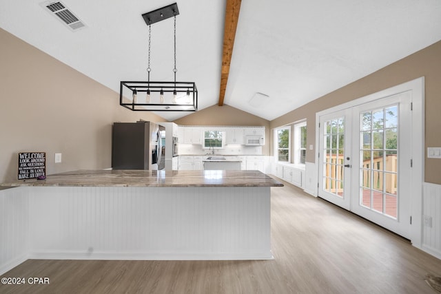 kitchen featuring white cabinetry, kitchen peninsula, stainless steel fridge, decorative light fixtures, and light wood-type flooring