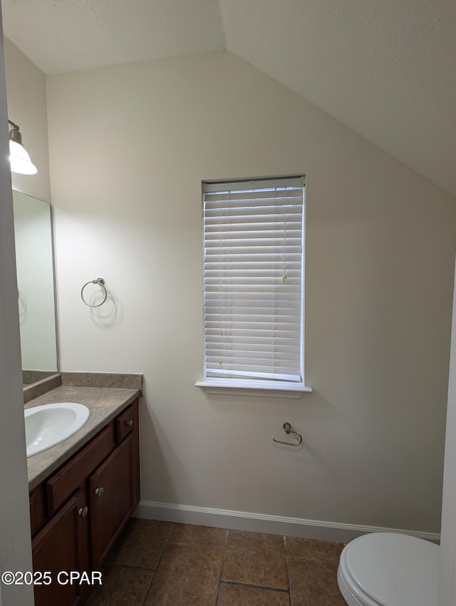 bathroom featuring vanity, toilet, and vaulted ceiling