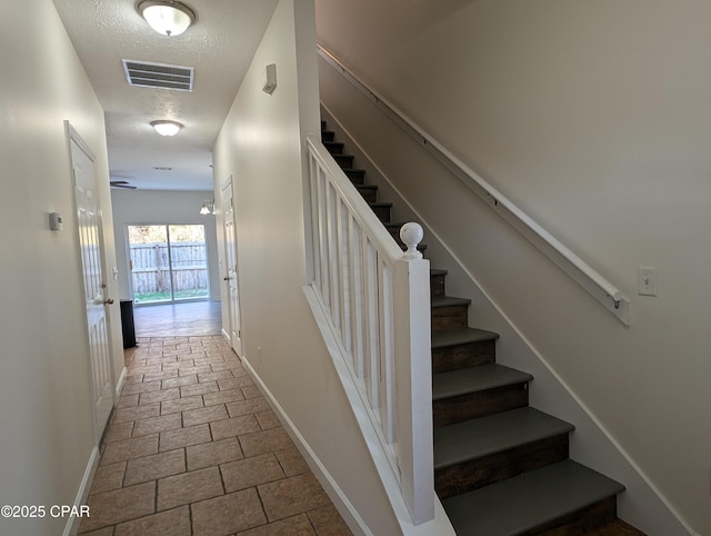 stairs featuring a textured ceiling and an inviting chandelier