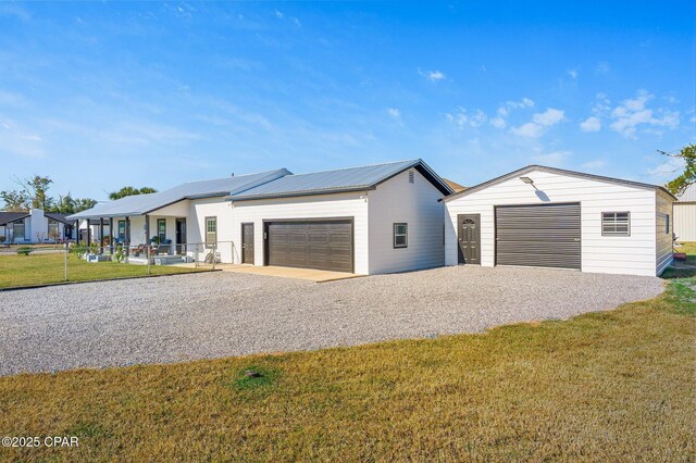 view of front facade featuring a garage, metal roof, gravel driveway, and a front yard
