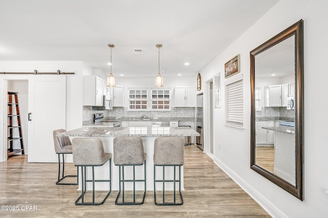 kitchen with a barn door, white cabinetry, and appliances with stainless steel finishes