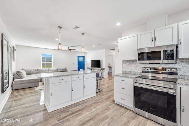 kitchen featuring a breakfast bar area, white cabinetry, pendant lighting, and stainless steel appliances