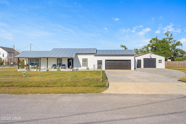 view of front of home featuring driveway, a front lawn, a garage, a fenced front yard, and metal roof