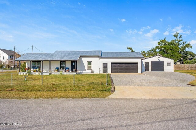 view of front of property featuring driveway, covered porch, a front lawn, a fenced front yard, and metal roof