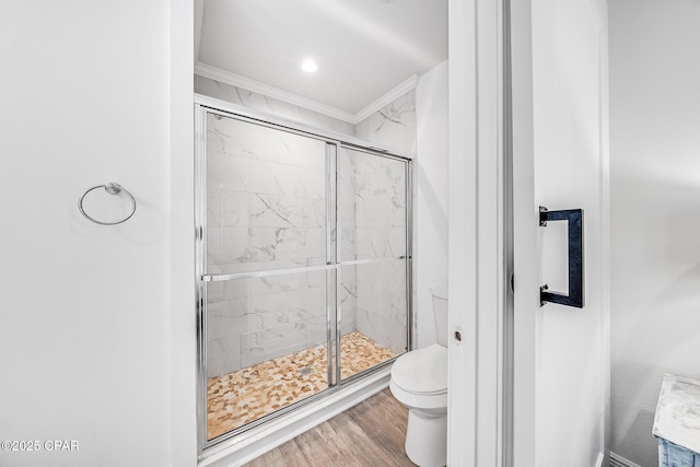 bathroom with hardwood / wood-style flooring, toilet, a shower with shower door, and ornamental molding