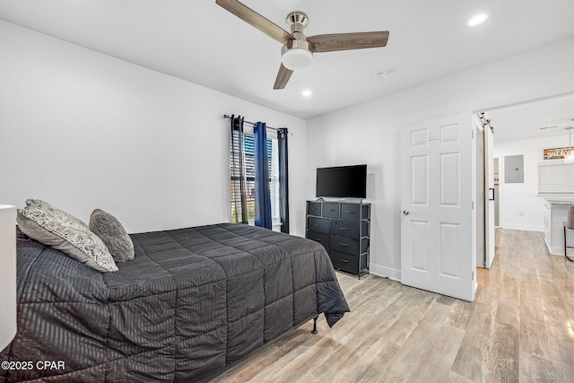 bedroom with ceiling fan, light hardwood / wood-style floors, and electric panel