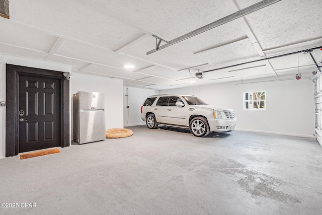 garage with stainless steel fridge and a garage door opener