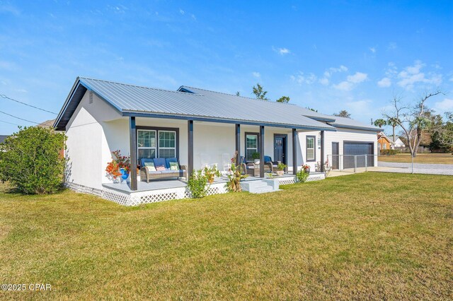 back of property featuring a garage, a yard, covered porch, concrete driveway, and metal roof