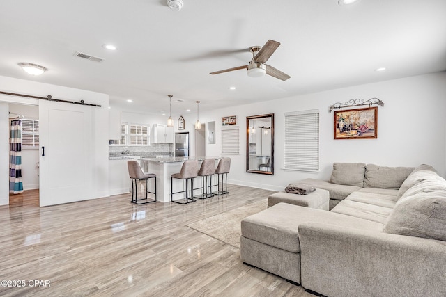 living room featuring a barn door and ceiling fan