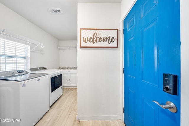 clothes washing area with cabinets and washing machine and clothes dryer