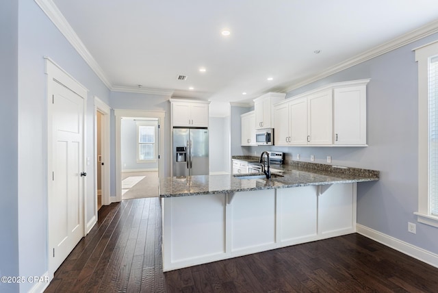 kitchen with kitchen peninsula, dark hardwood / wood-style flooring, stainless steel appliances, sink, and white cabinetry