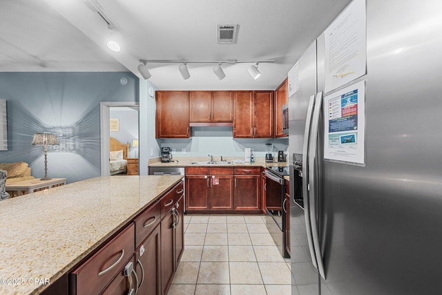 kitchen with light stone countertops, sink, light tile patterned flooring, and stainless steel appliances