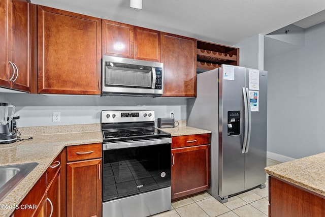 kitchen with appliances with stainless steel finishes, sink, light tile patterned floors, and light stone counters