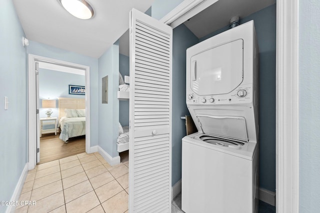 laundry area with light tile patterned floors and stacked washer / dryer