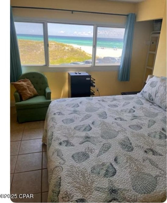 bedroom featuring tile patterned flooring, a water view, and multiple windows