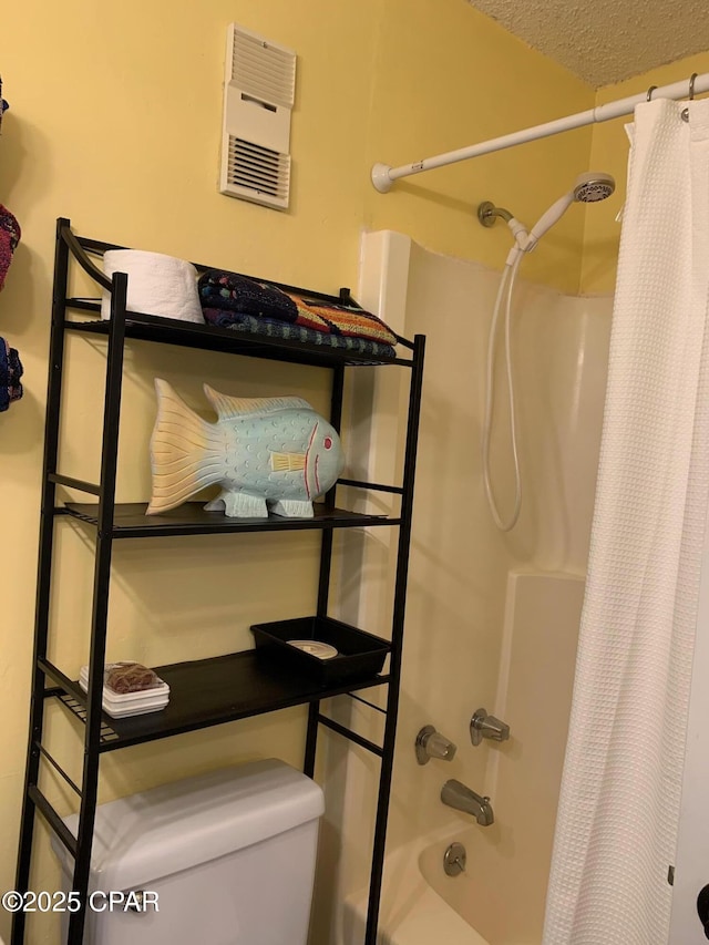 bathroom with shower / bath combo, toilet, and a textured ceiling